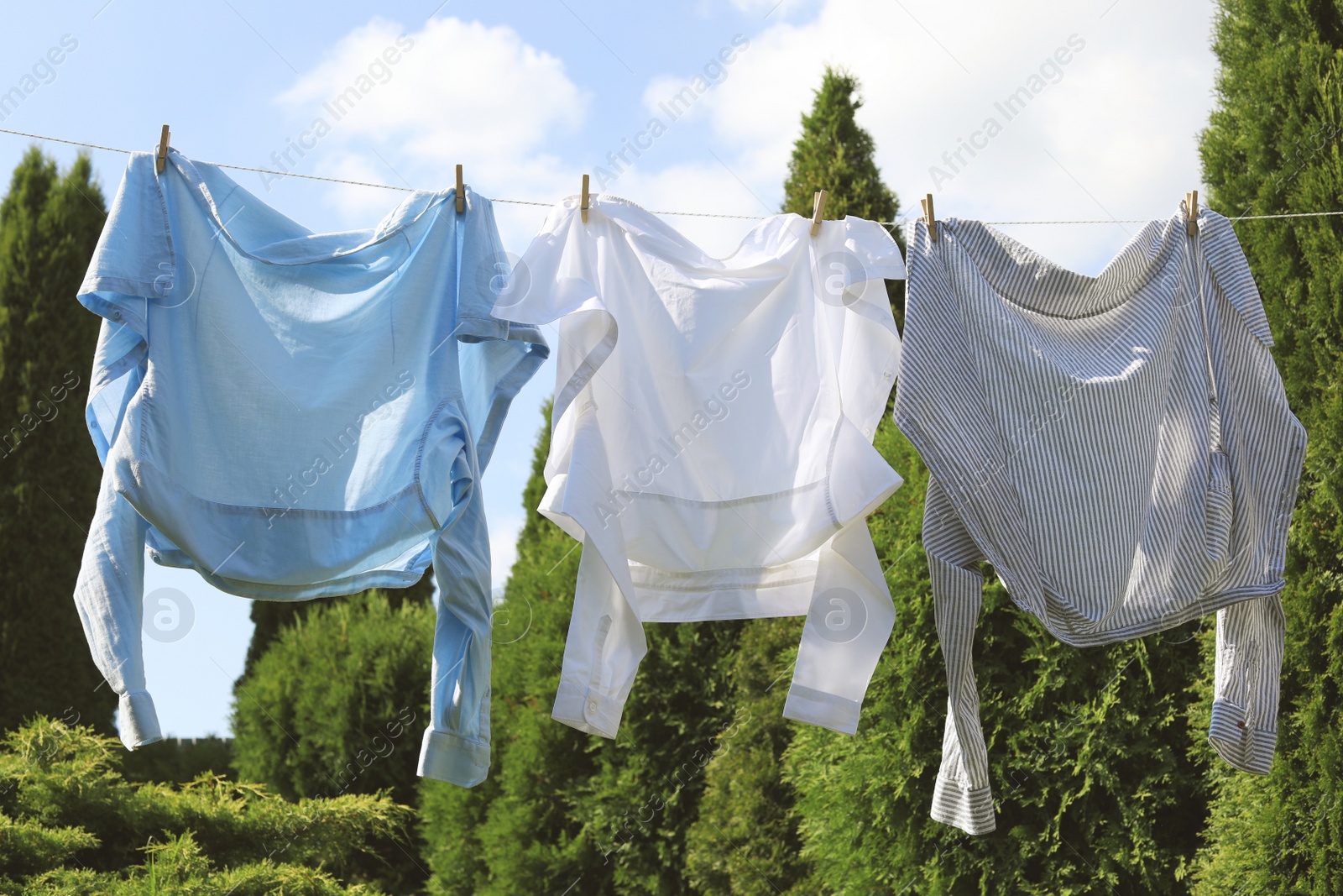 Photo of Clean clothes hanging on washing line in garden. Drying laundry