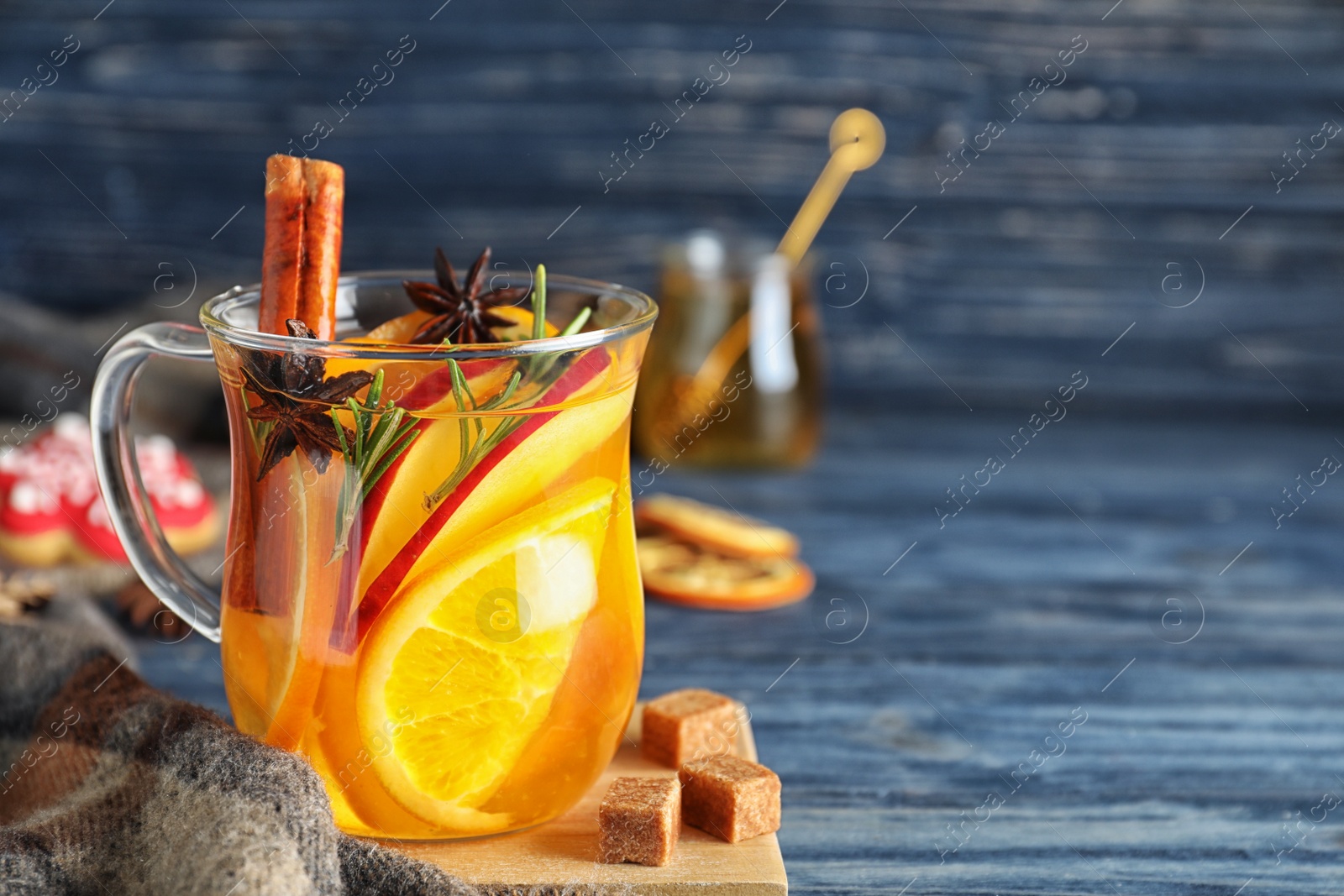 Photo of Aromatic mulled wine on blue wooden table. Space for text