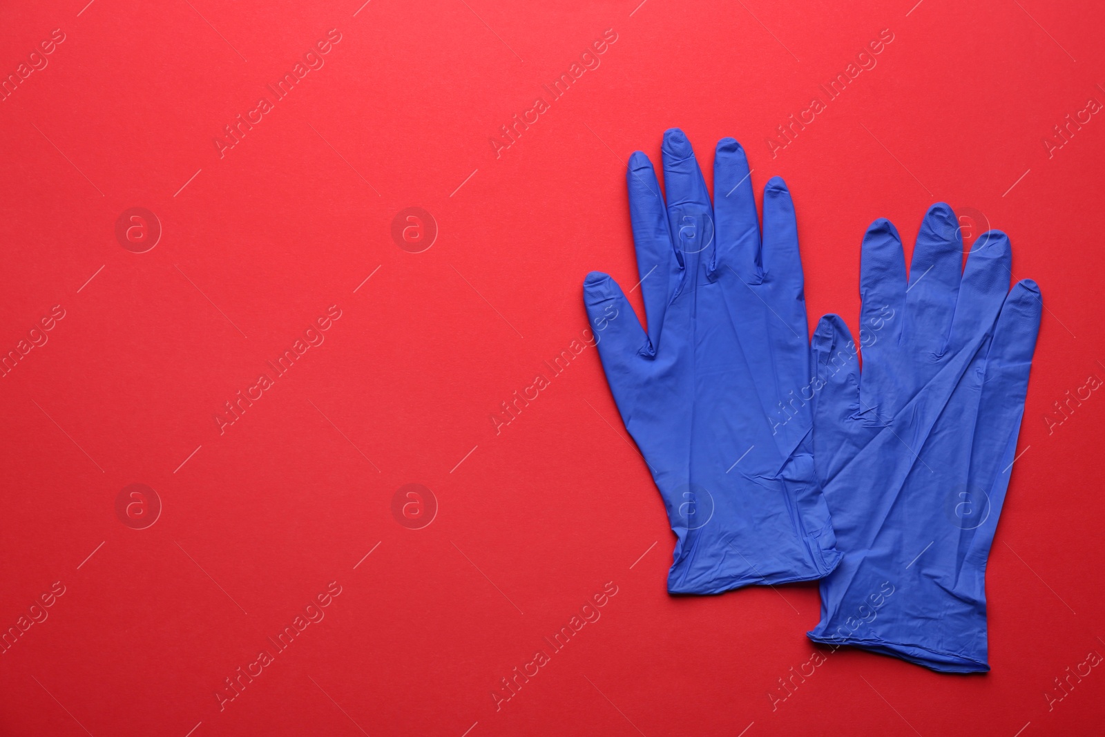 Photo of Pair of medical gloves on red background, flat lay. Space for text