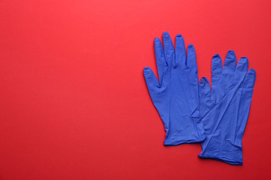 Photo of Pair of medical gloves on red background, flat lay. Space for text