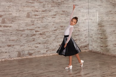 Adorable little girl dancing in studio, space for text
