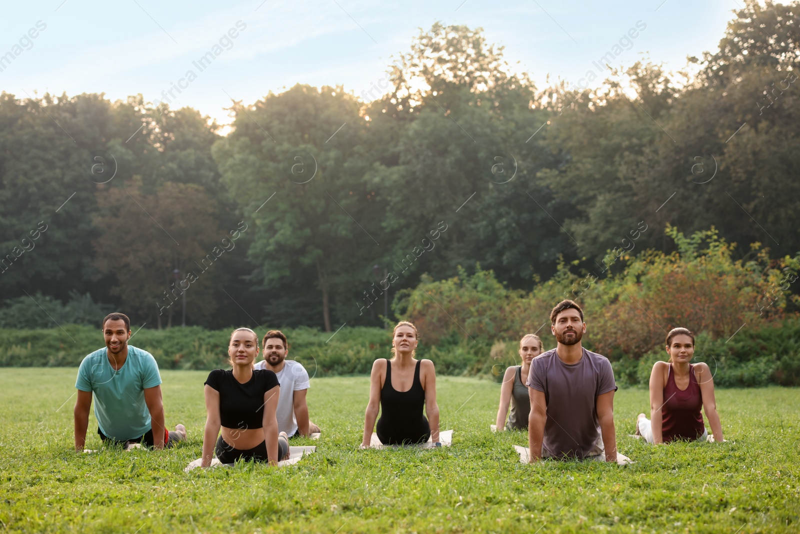 Photo of Group of people practicing yoga on mats outdoors