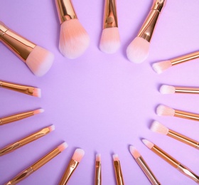 Photo of Flat lay composition with set of professional makeup brushes on lilac background. Space for text