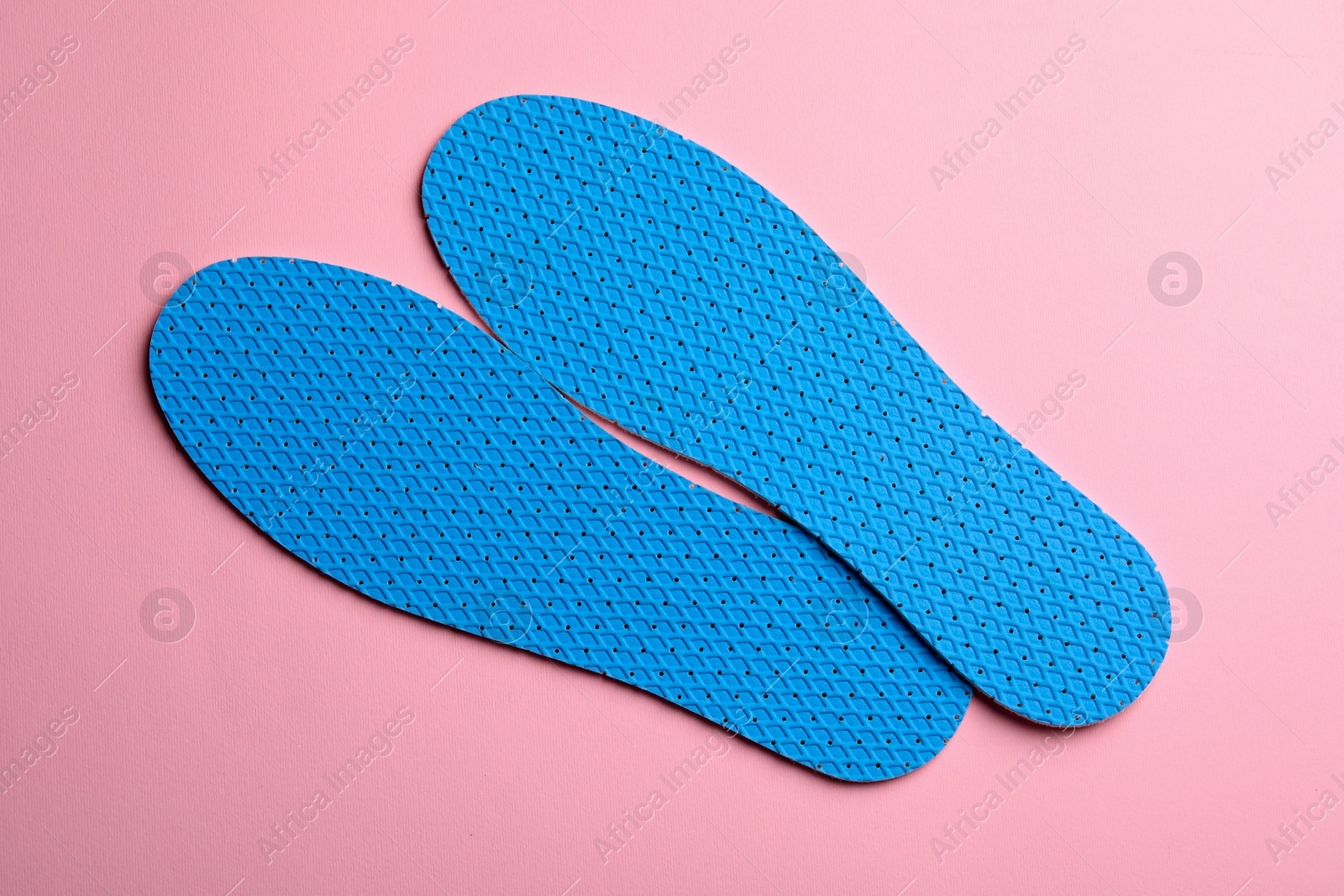 Photo of Pair of light blue breathable shoe insoles on pink background, view from above