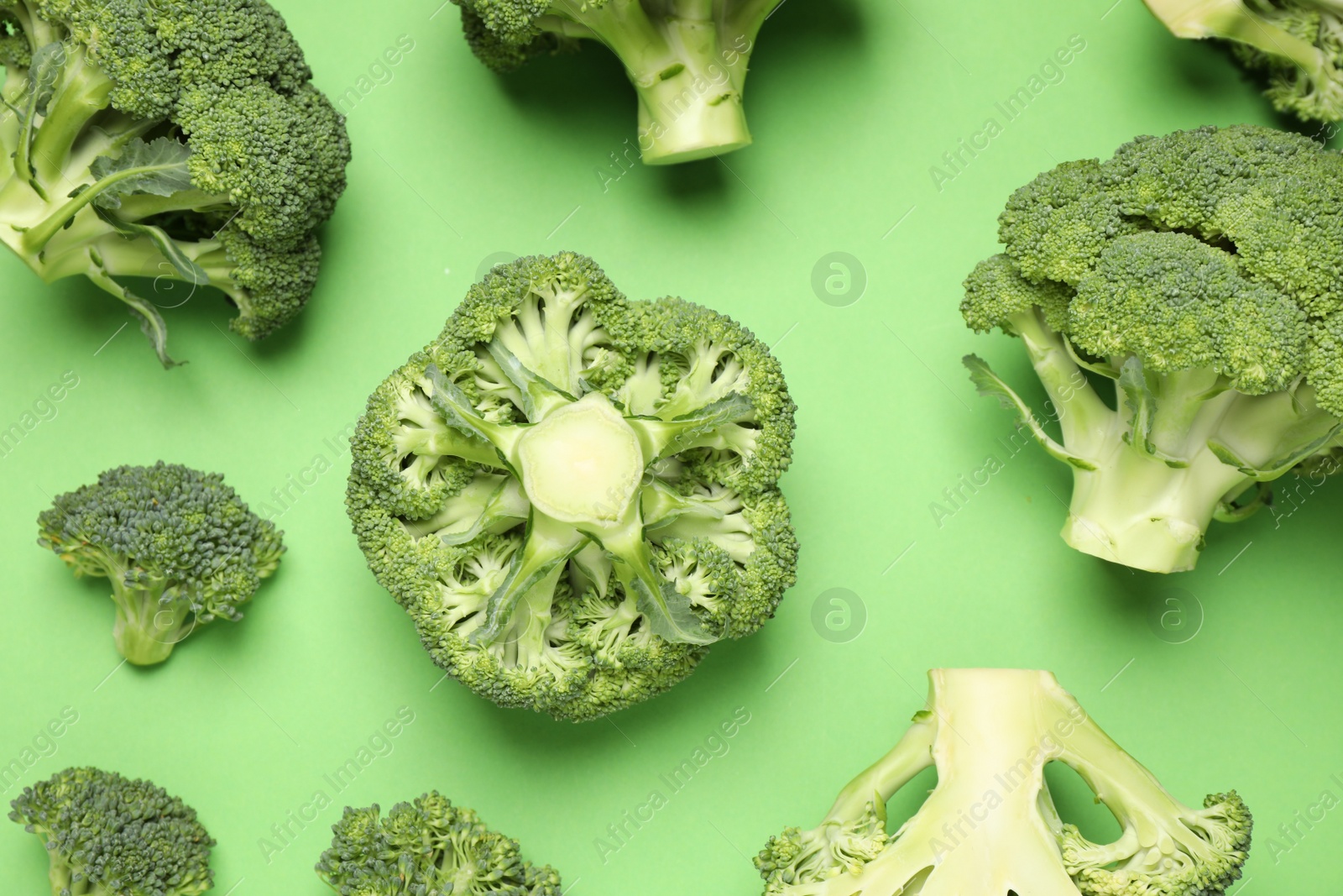 Photo of Fresh broccoli on green background, flat lay