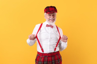 Portrait of grandpa with stylish hat and bowtie on yellow background