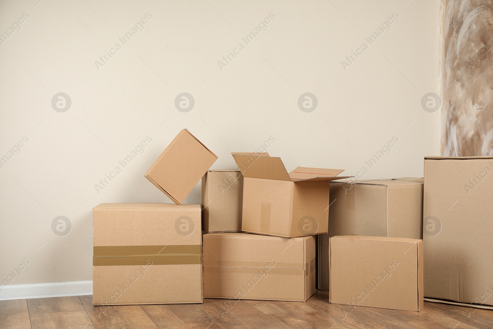 Photo of Pile of cardboard boxes near light wall indoors