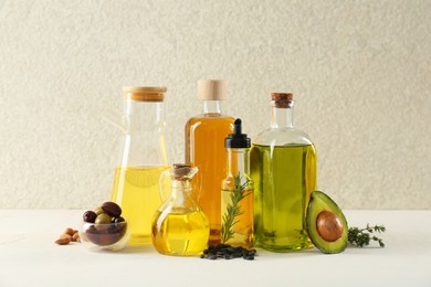 Photo of Vegetable fats. Different cooking oils in glass bottles and ingredients on white table