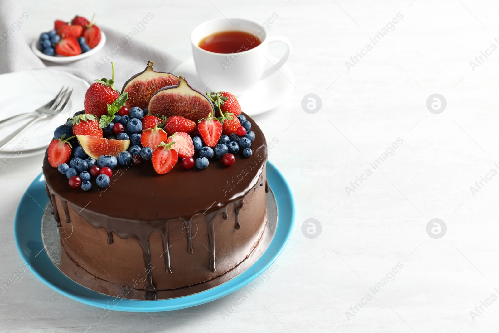 Photo of Fresh delicious homemade chocolate cake with berries on light table. Space for text