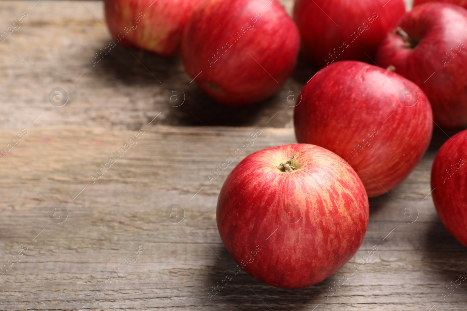 Photo of Fresh red apples on wooden table, closeup. Space for text