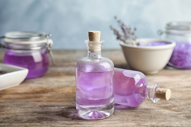 Photo of Bottles with natural lavender oil on table against blurred background