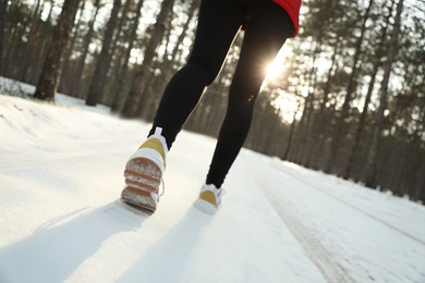 Photo of Woman running in winter forest, closeup. Outdoors sports exercises