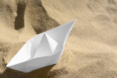 One white paper boat on sandy beach, closeup. Space for text