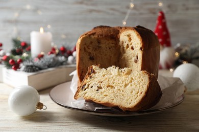 Photo of Delicious cut Panettone cake and Christmas decor on light wooden table. Traditional Italian pastry