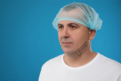 Photo of Mature man with marks on face against blue background. Double chin removal