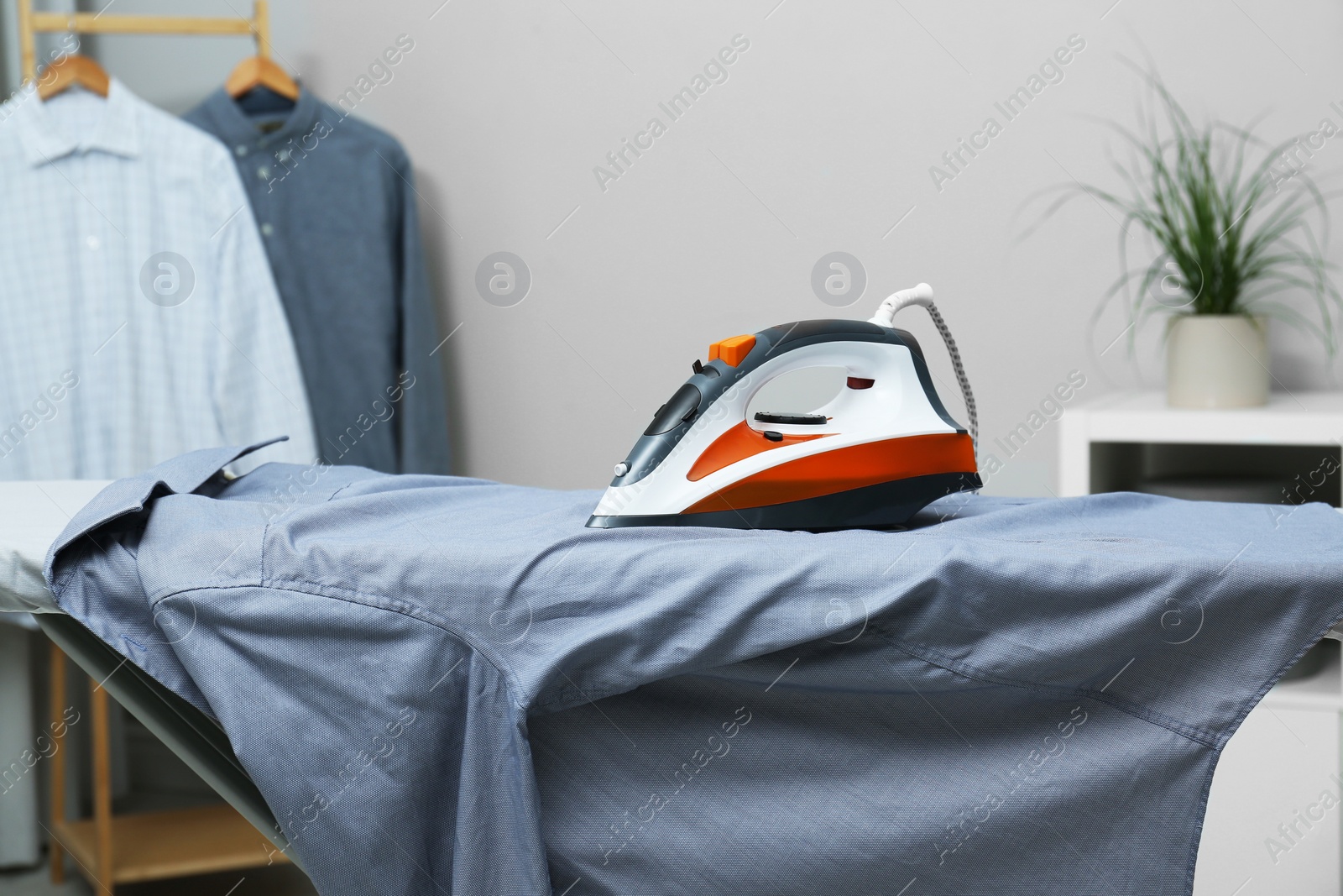 Photo of Modern iron and grey shirt on board indoors