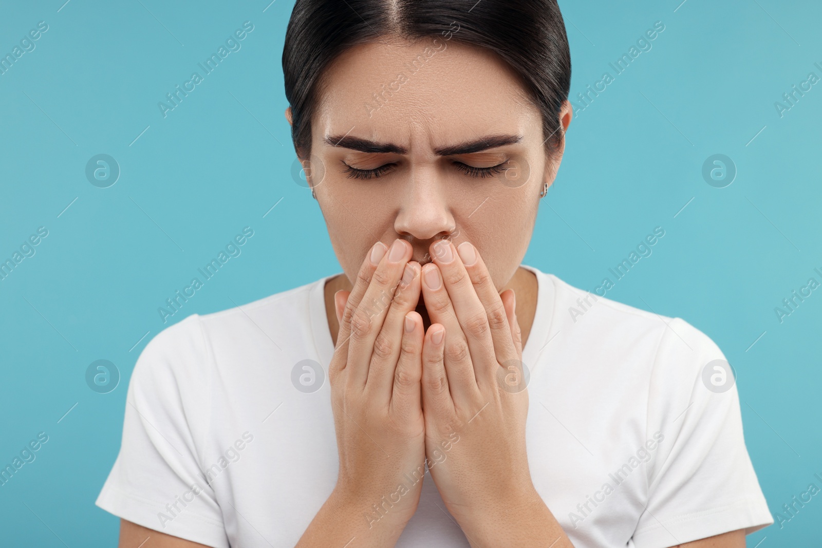 Photo of Woman coughing on light blue background. Cold symptoms