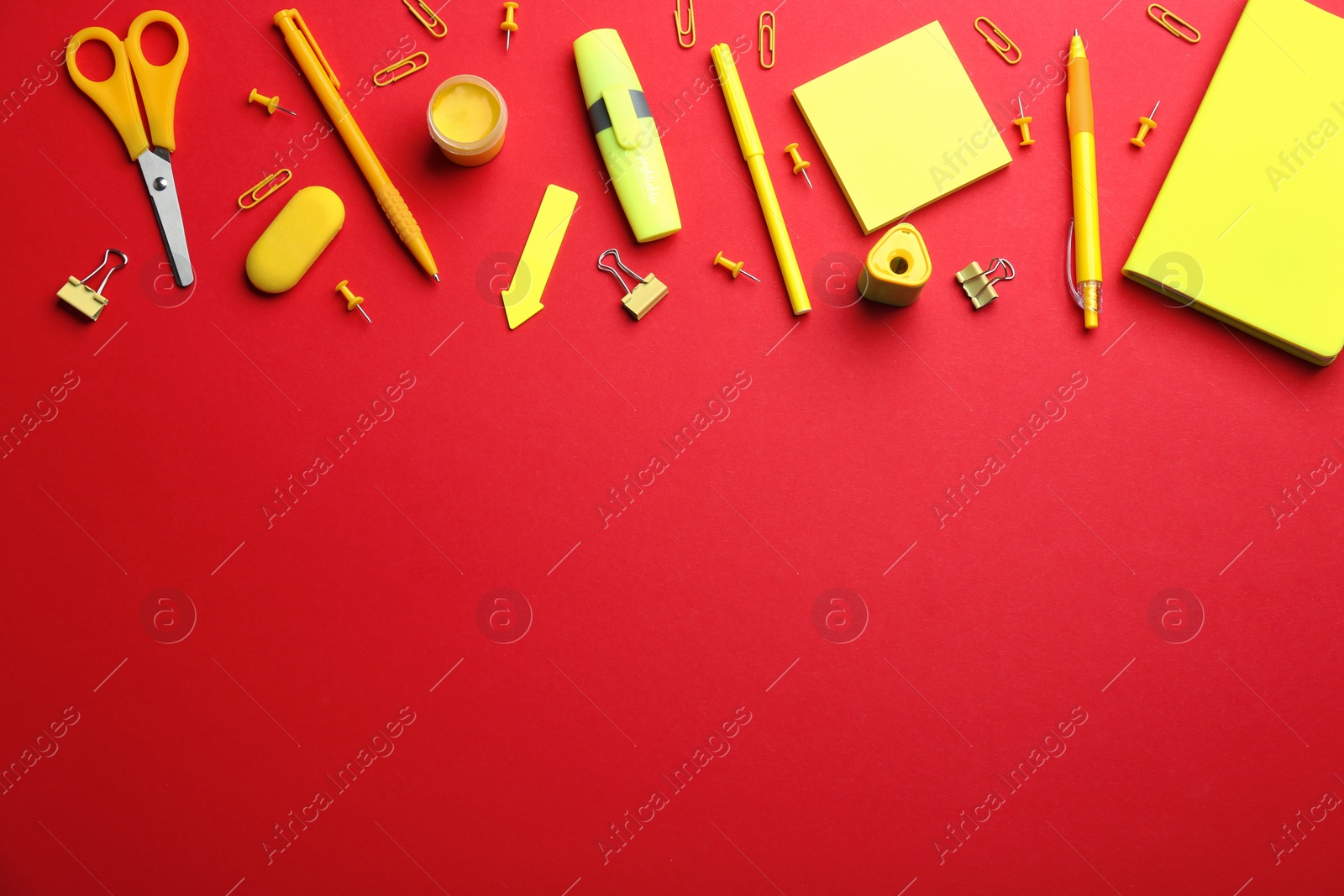 Photo of Yellow school stationery on red background, flat lay. Space for text