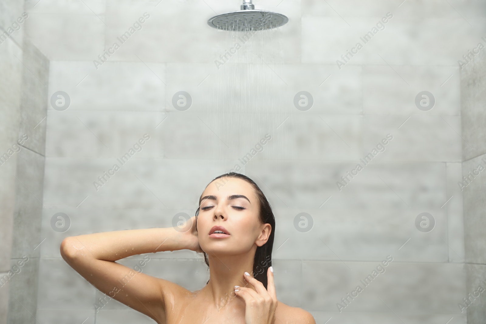 Photo of Beautiful young woman taking shower in spa center