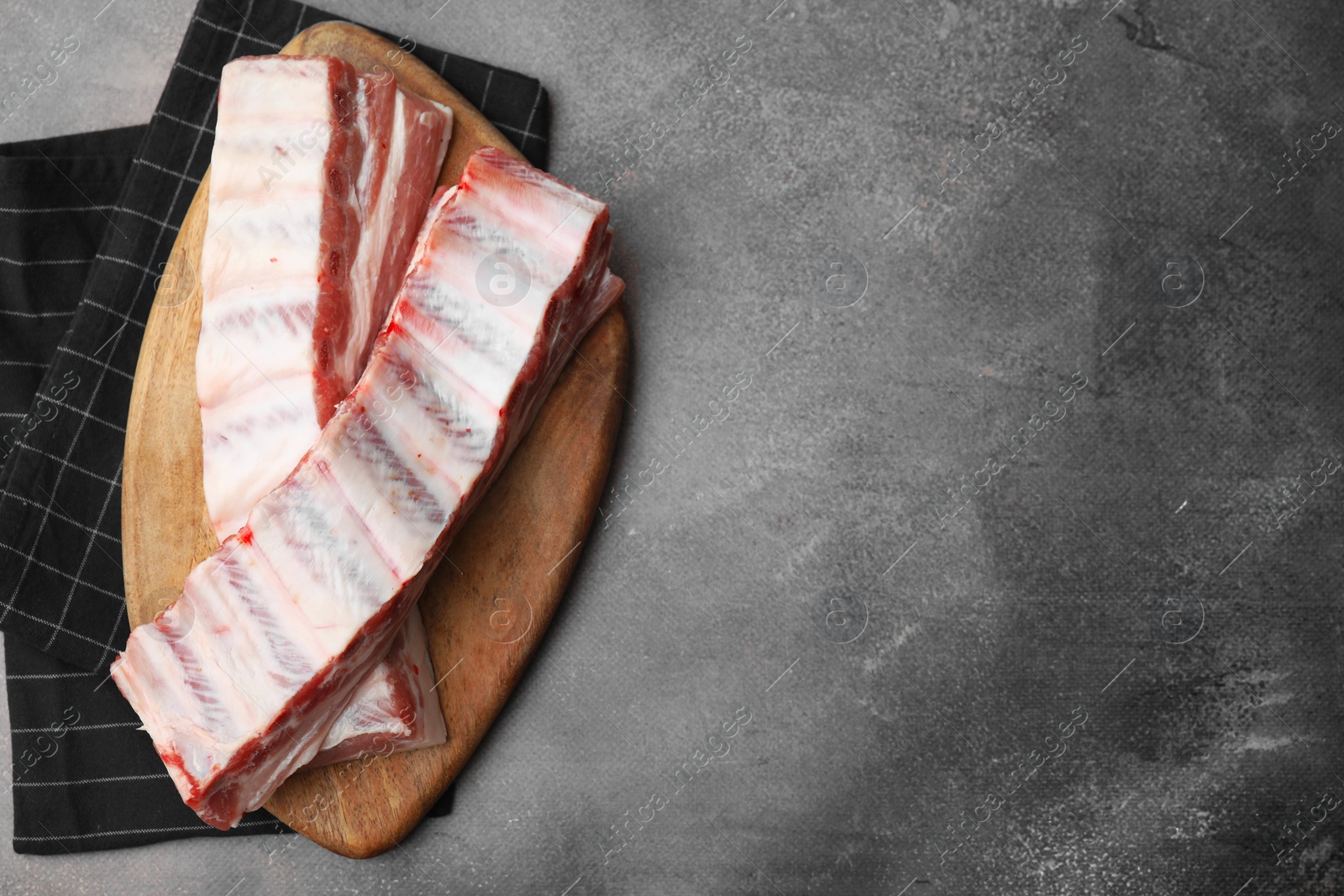 Photo of Raw pork ribs on grey table, top view. Space for text