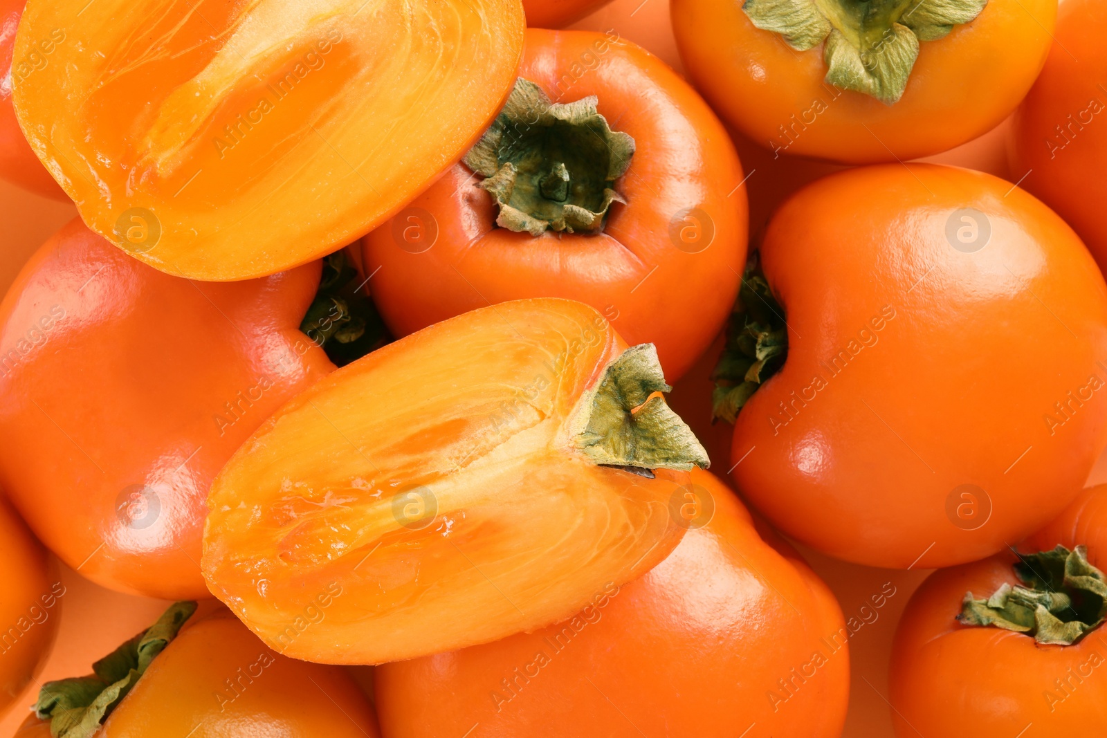 Photo of Whole and cut delicious ripe juicy persimmons as background, top view