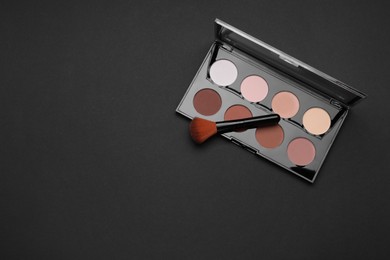 Photo of Contouring palette and brush on black background, top view with space for text. Professional cosmetic product