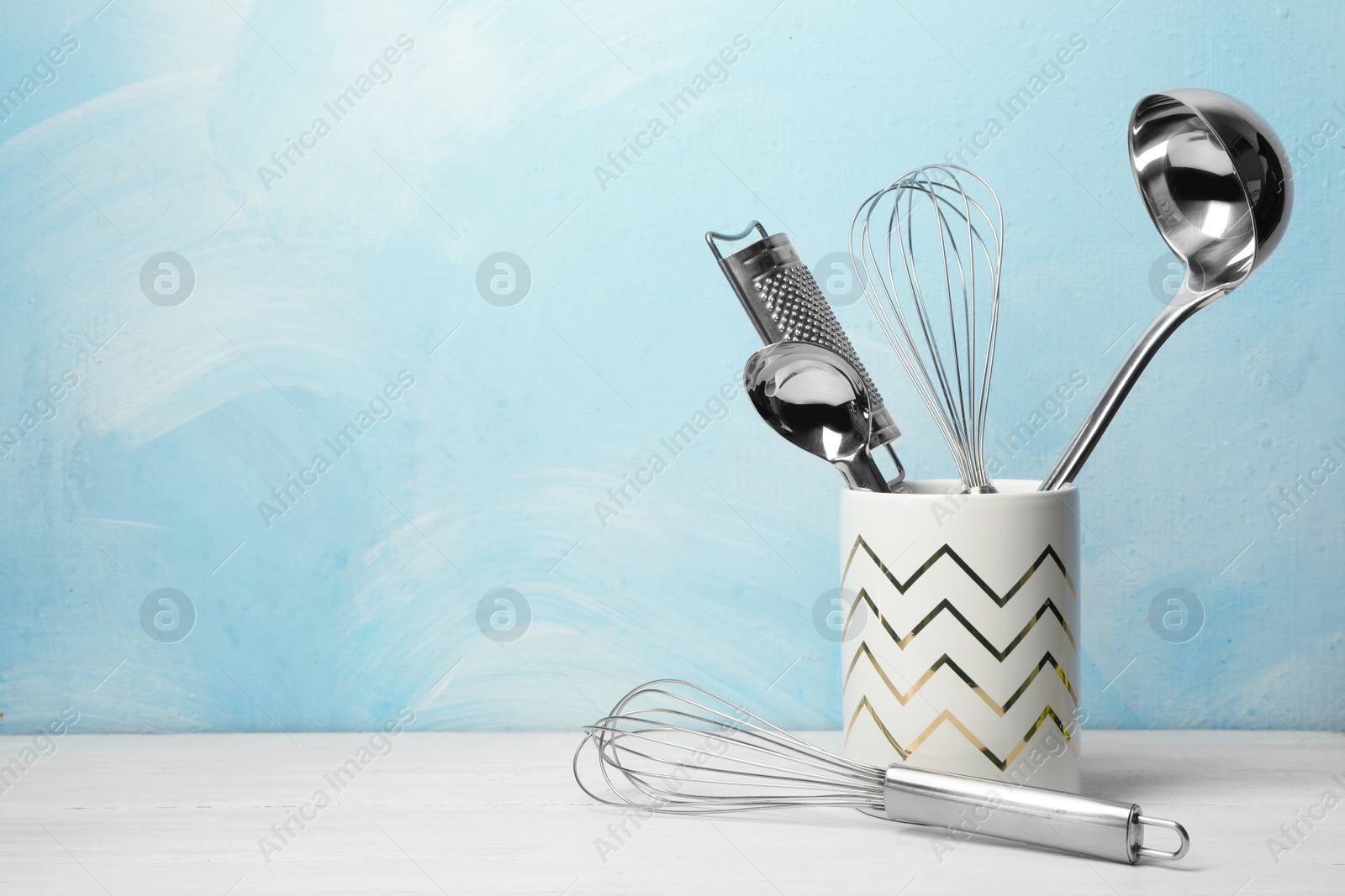 Photo of Holder with clean kitchen utensils on table. Space for text