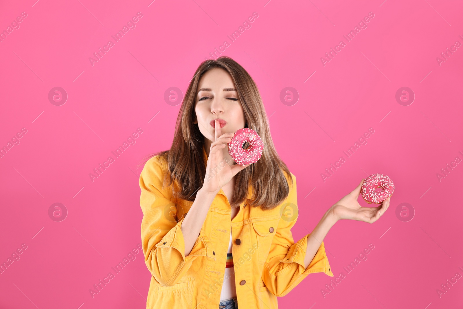 Photo of Beautiful young woman with donuts on pink background