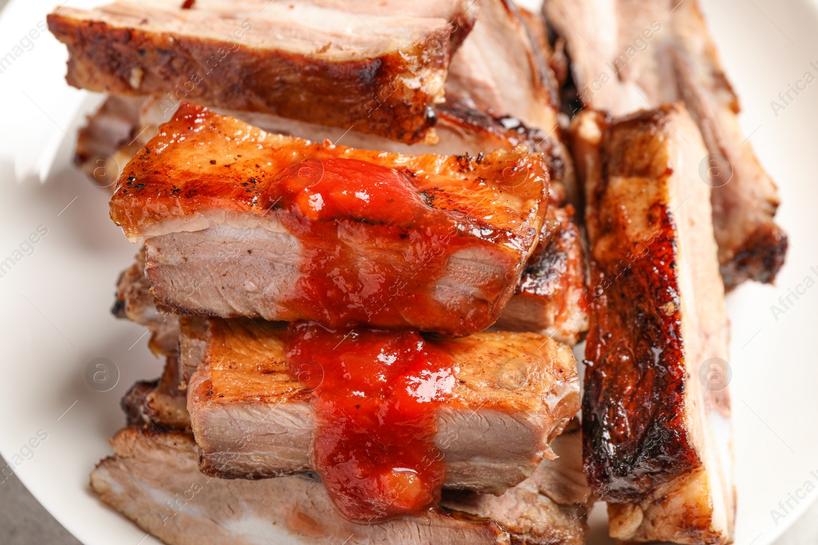 Photo of Delicious grilled ribs with sauce on table, closeup