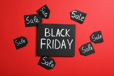 Phrase Black Friday and tags with word Sale on red background, flat lay