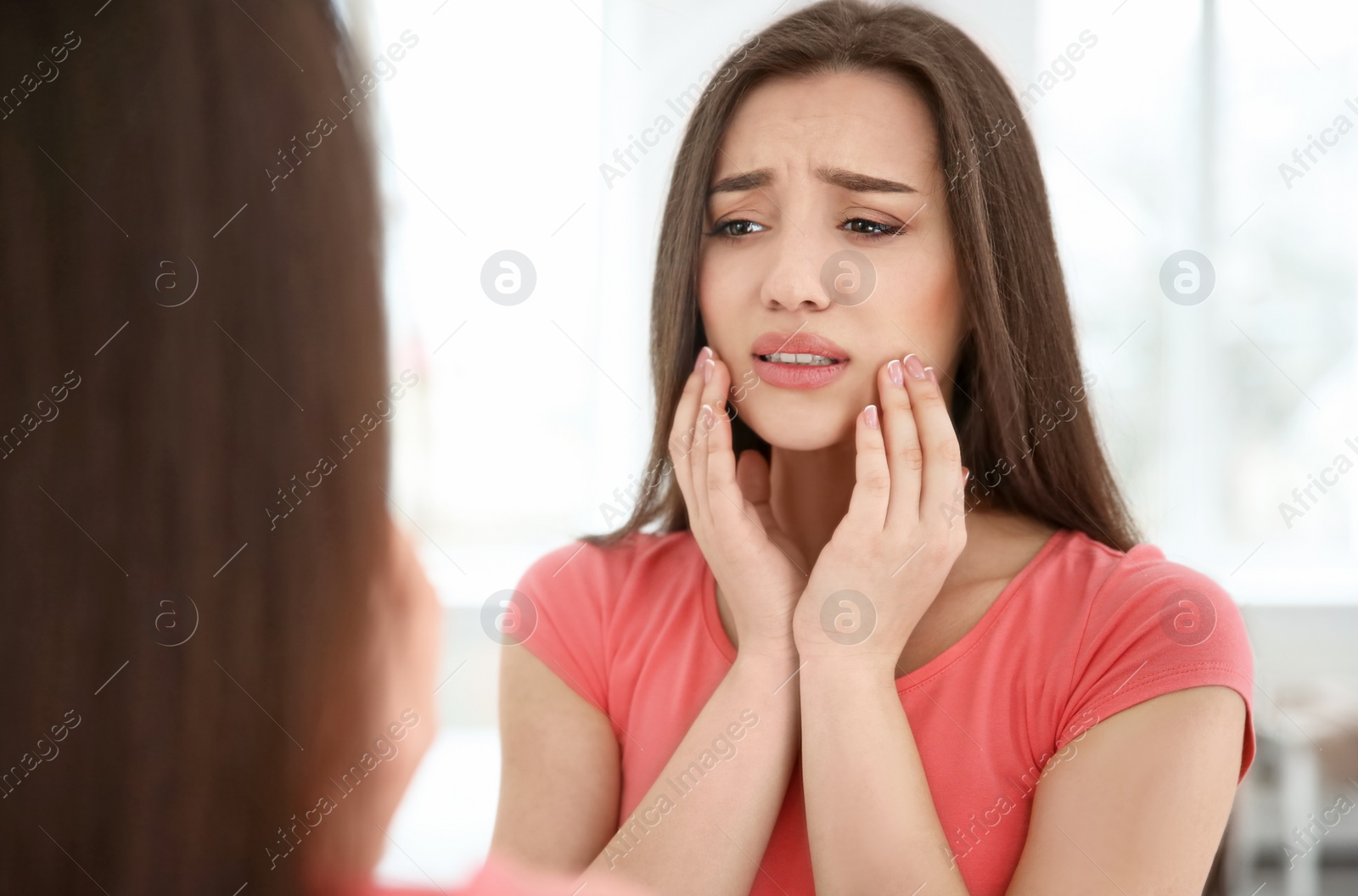 Photo of Reflection of woman with sensitive teeth in mirror indoors