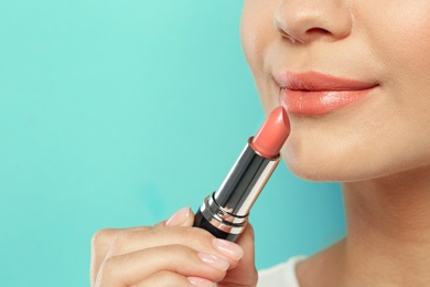 Photo of Beautiful woman applying nude lipstick on color background, closeup. Space for text