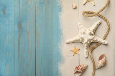 Beautiful sea stars, shells, rope and sand on blue wooden background, flat lay. Space for text