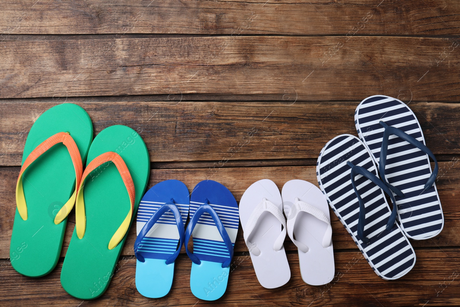 Photo of Many different flip flops on wooden background, flat lay. Space for text