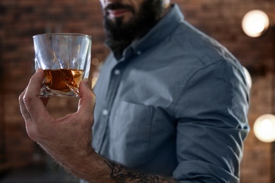 Man with glass of whiskey indoors, closeup
