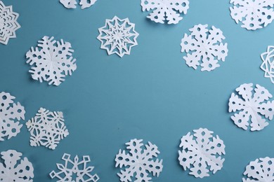 Many paper snowflakes on turquoise background, flat lay. Space for text