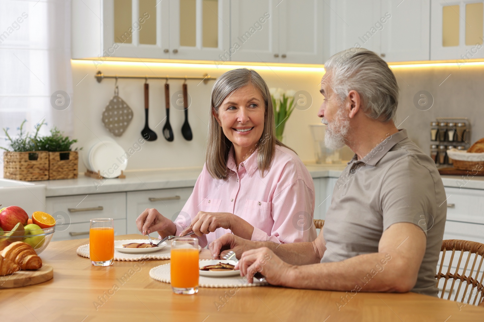 Photo of Happy senior couple having breakfast at home