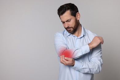 Image of Man suffering from pain in elbow on grey background. Space for text