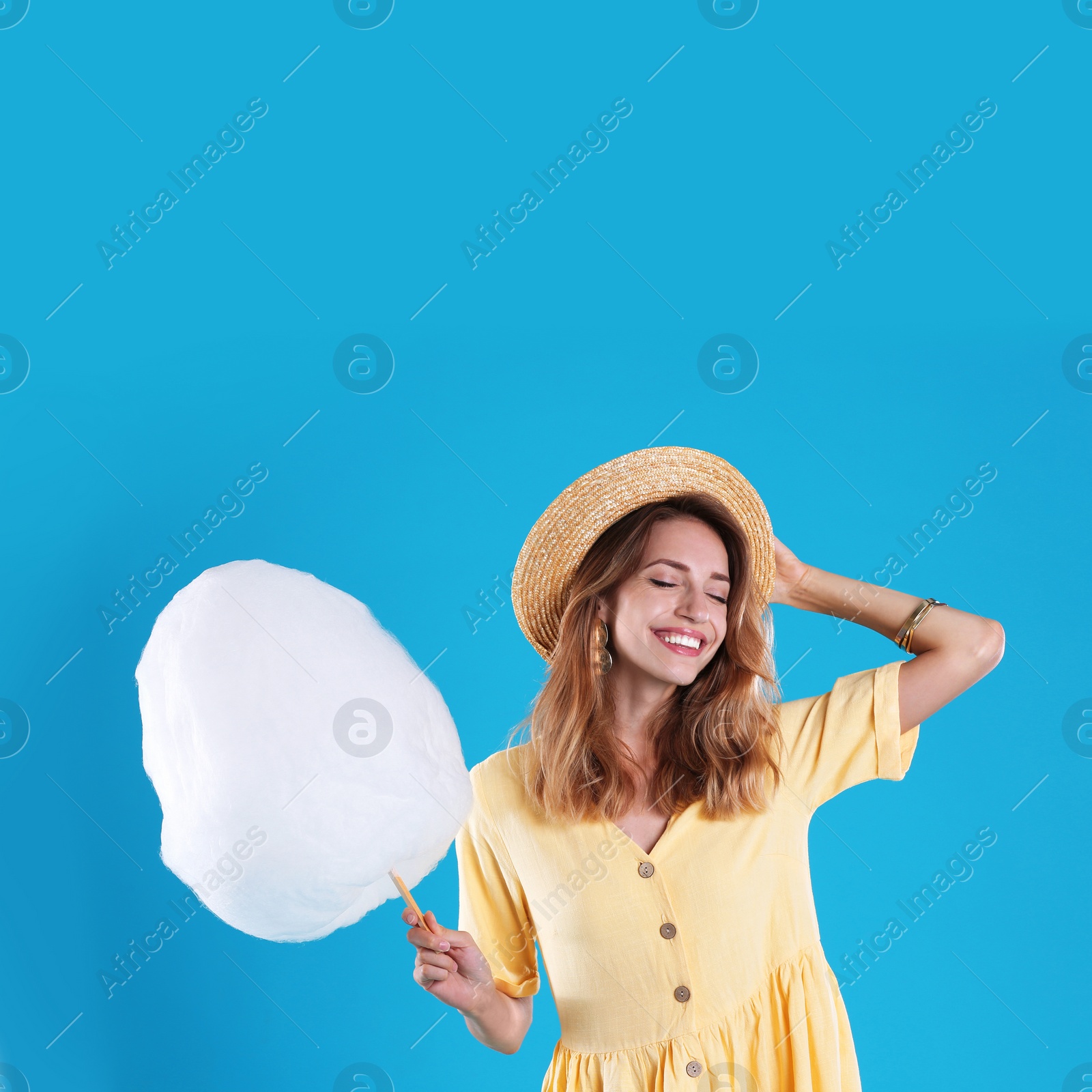 Photo of Happy young woman with cotton candy on blue background