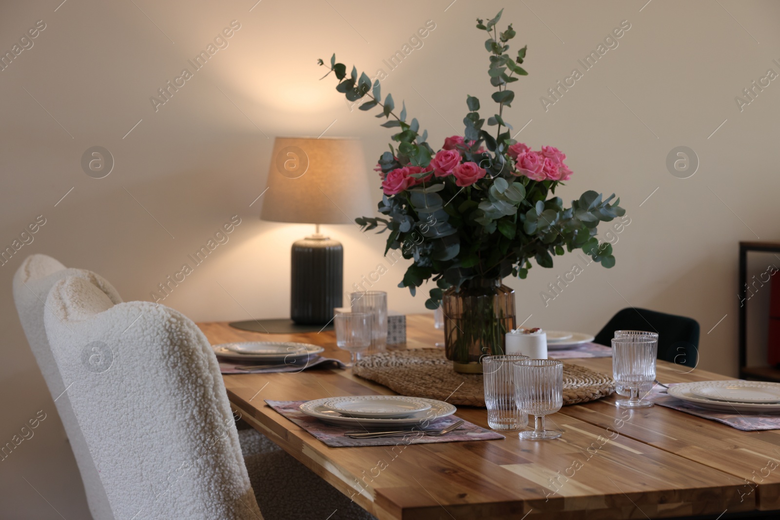 Photo of Beautiful table setting with bouquet indoors. Roses and eucalyptus branches in vase