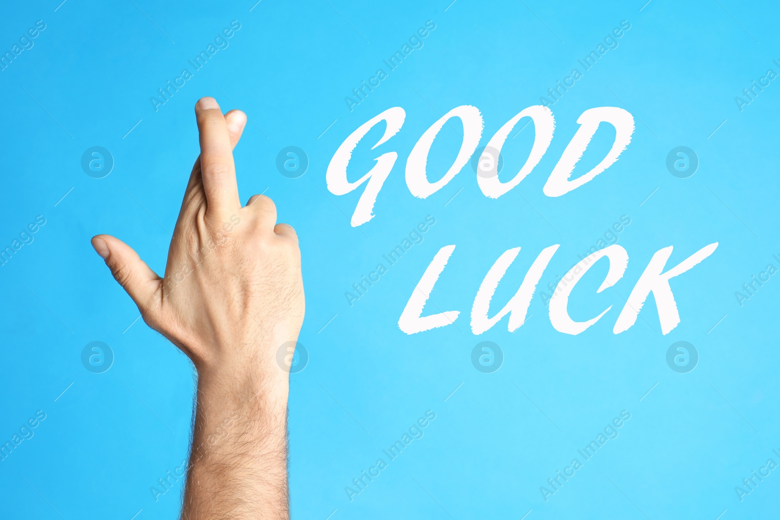 Image of Man with crossed fingers on light blue background, closeup. Good luck superstition