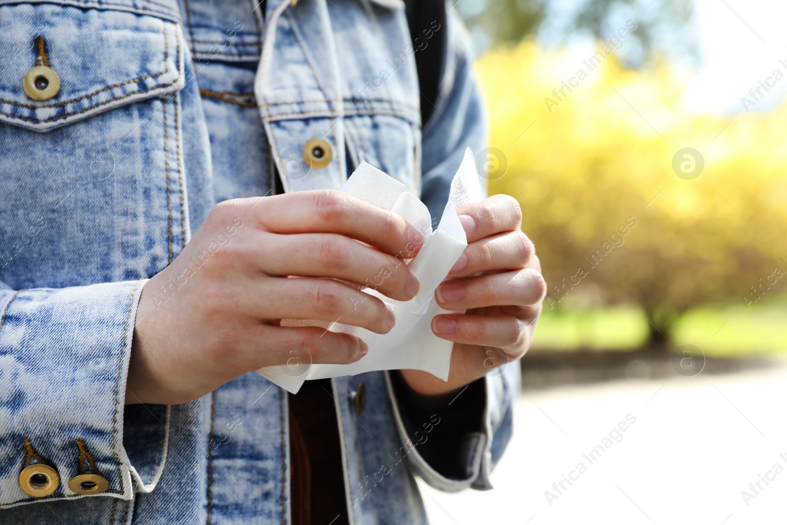 Photo of Woman wiping hands with paper napkin outdoors, closeup