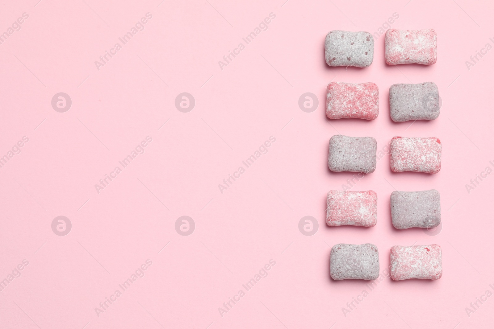 Photo of Tasty colorful bubble gums on pink background, flat lay. Space for text