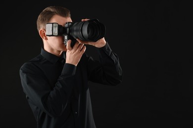 Photo of Professional photographer taking picture on black background, space for text