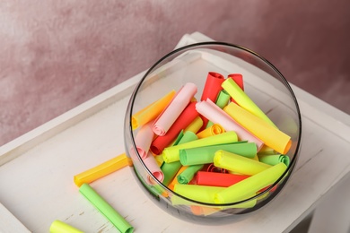 Photo of Colorful paper pieces for lottery in glass vase on wooden table