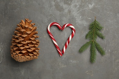 Pinecone, heart made with candy canes and fir branch on grey background, flat lay