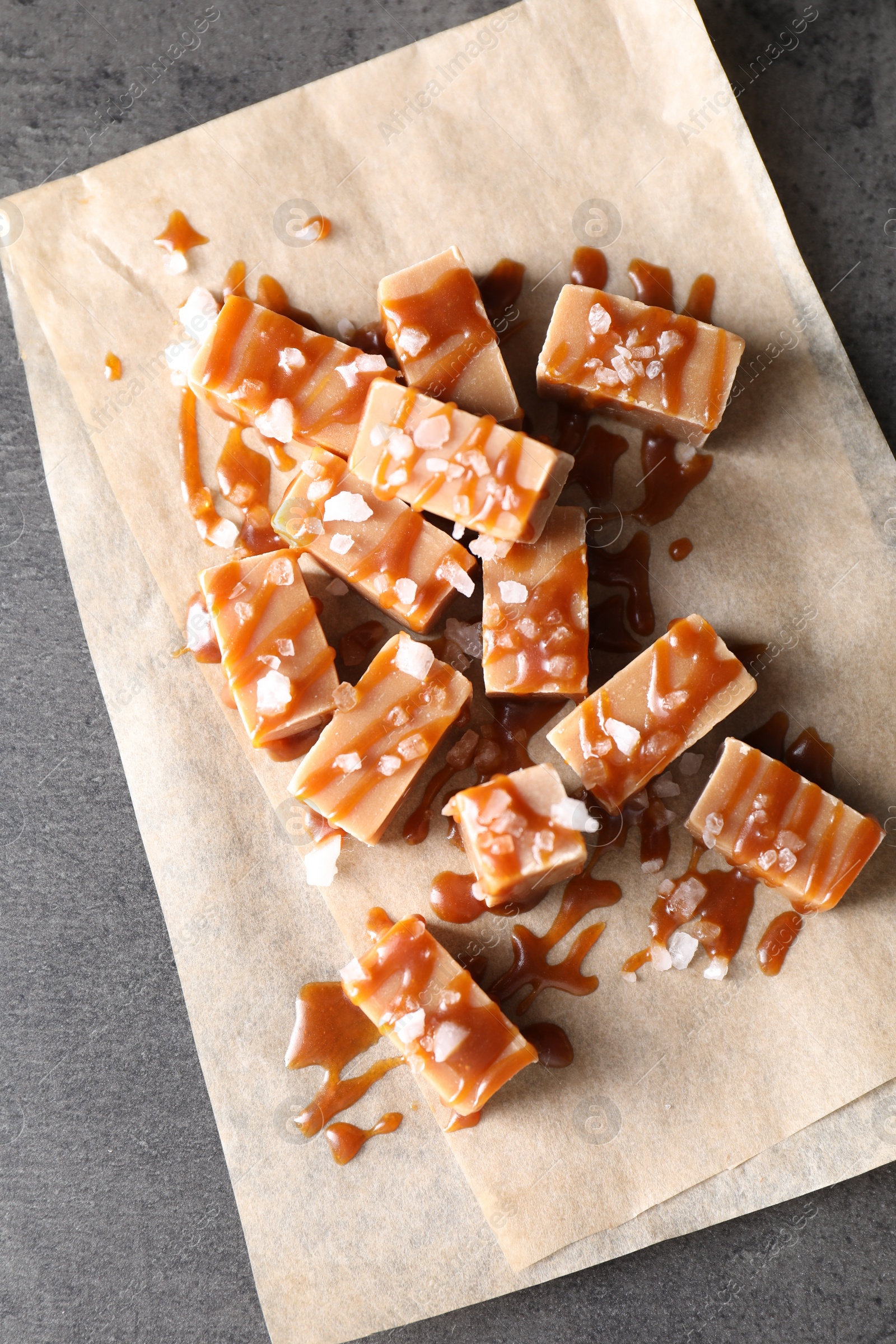 Photo of Tasty candies, caramel sauce and salt on grey table, top view