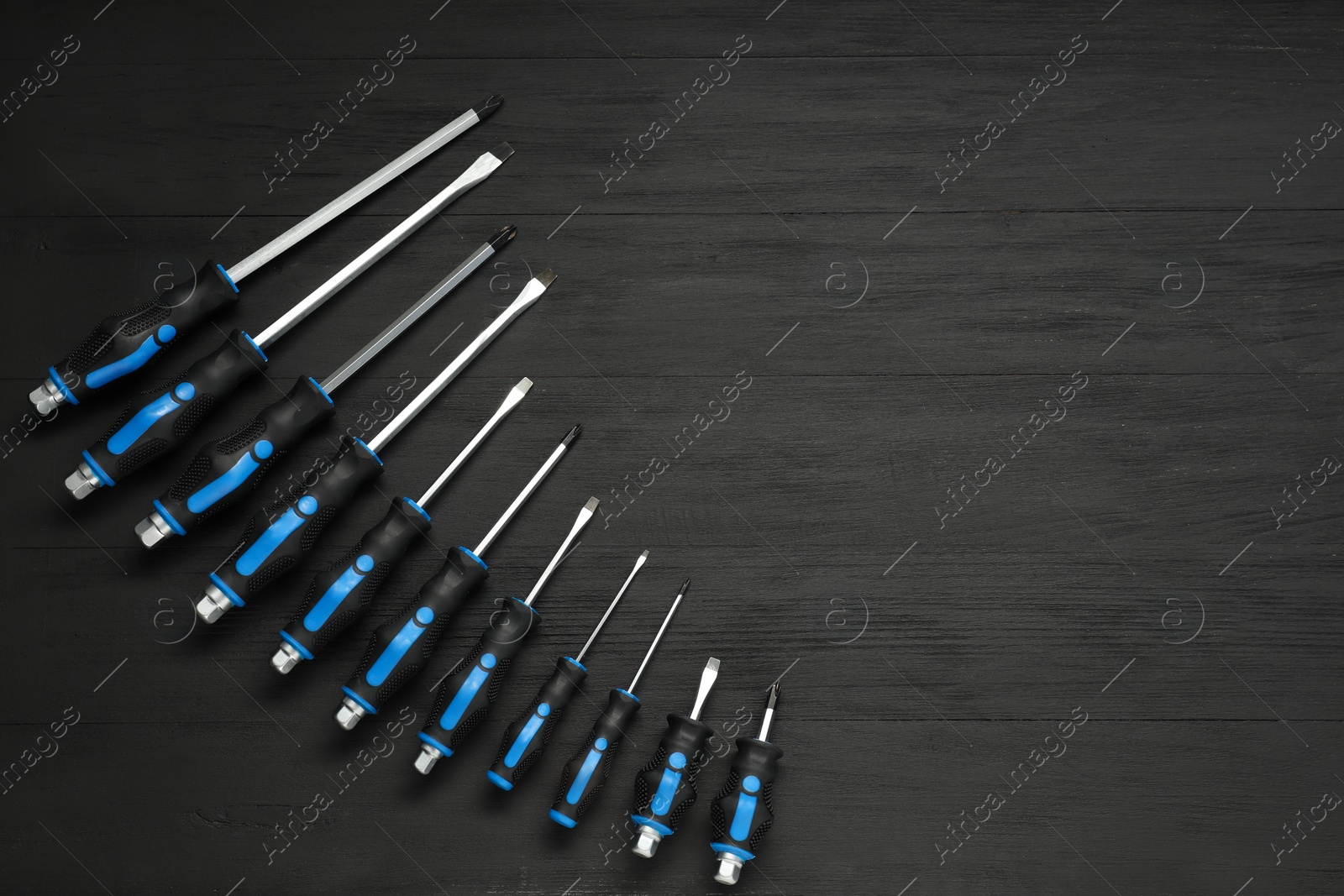 Photo of Set of screwdrivers on black wooden table, top view. Space for text