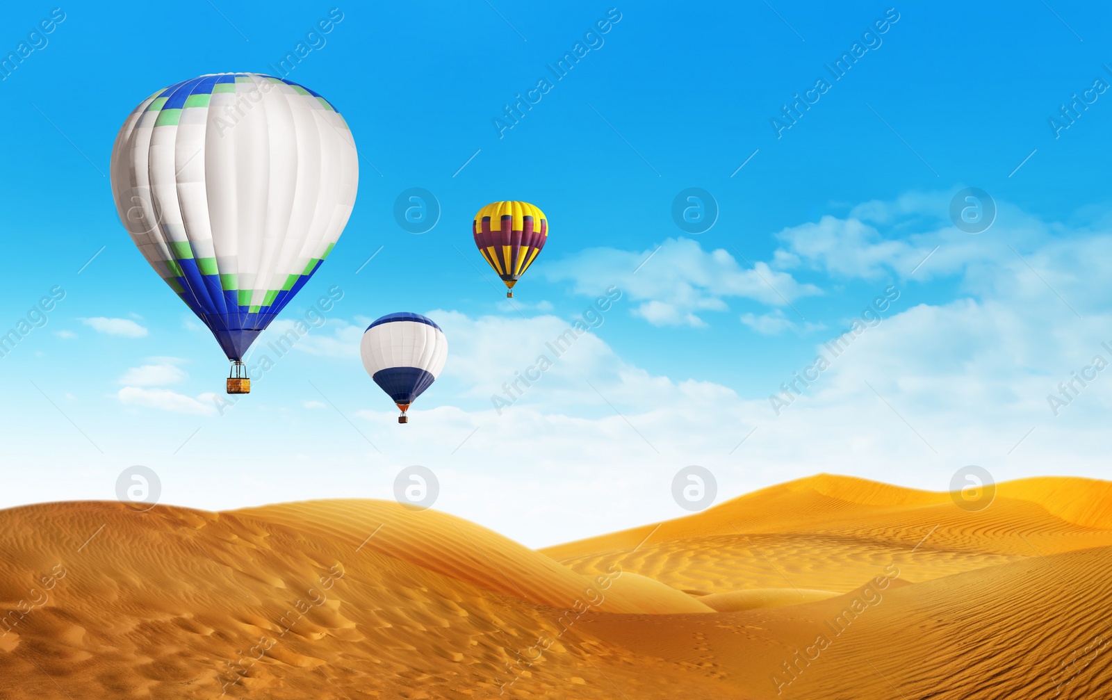 Image of Bright hot air balloons flying in blue sky over sandy desert