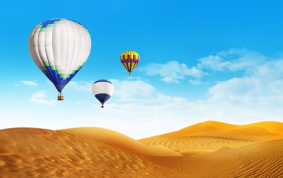 Image of Bright hot air balloons flying in blue sky over sandy desert